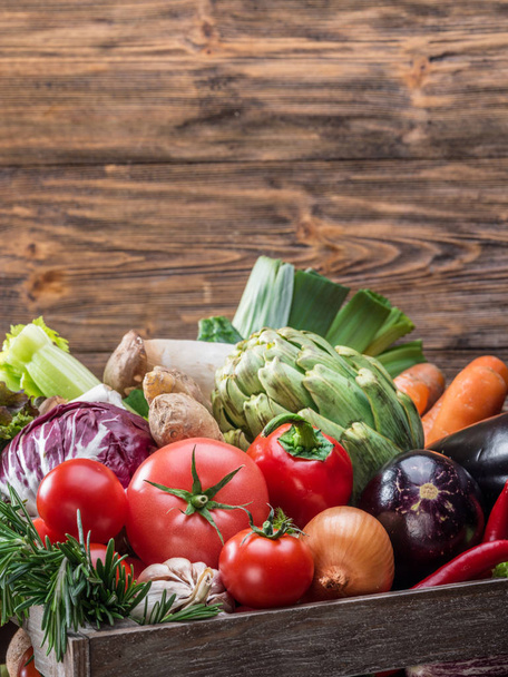 Fresh multi-colored vegetables in wooden crate. Wooden background. - Φωτογραφία, εικόνα
