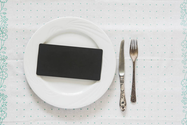 Placa vazia branca com garfo de prata vintage e faca em uma mesa de bolinhas
 - Foto, Imagem