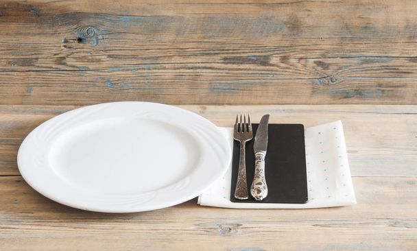 White empty plate with vintage silver ware fork and knife on a polka dot tableclot - Фото, изображение