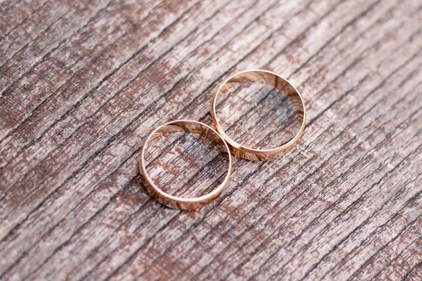 Dois anéis de casamento dourados no fundo de madeira
 - Foto, Imagem