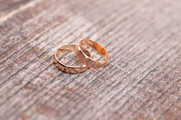 Два золотых обручальных кольца на деревянном фоне
 - Фото, изображение