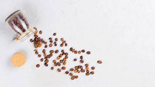 scattered coffee beans from a jar and little jar with beans  on a light concrete background, top view, copy space - Foto, afbeelding