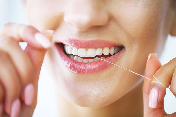 Teeth Care. Beautiful Smiling Woman Flossing Healthy White Teeth. High Resolution Image - Zdjęcie, obraz
