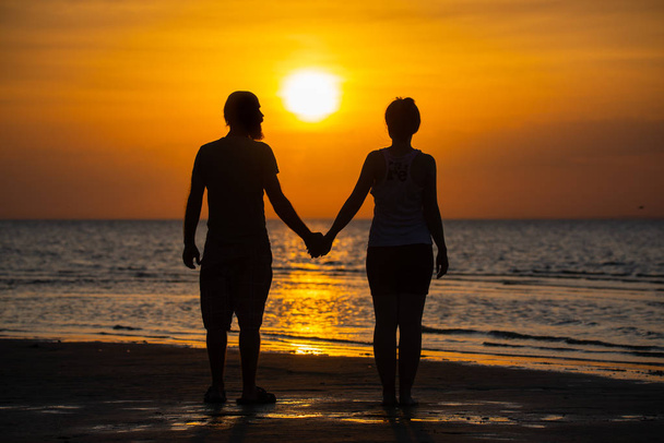 Пара коханців тримає руку зі сходом сонця
. - Фото, зображення
