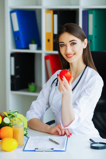 Υγεία. Διατροφή και υγιεινή. Ο γιατρός διαιτολόγος κρατώντας φρέσκες ντομάτες για τα χέρια και τα χαμόγελα. Όμορφη και νεαρό γιατρό. Υψηλή ανάλυση - Φωτογραφία, εικόνα