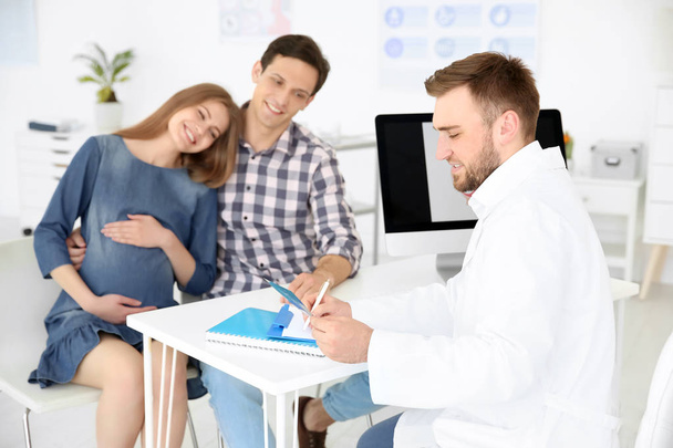 Gynecology consultation. Doctor showing ultrasound of baby to future parents in clinic - Photo, image