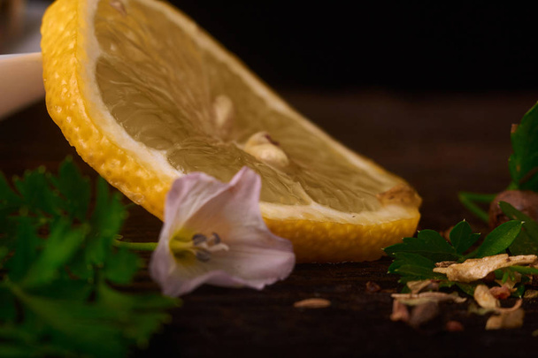 A slice of lemon with spices on a wooden background near the plate - Zdjęcie, obraz