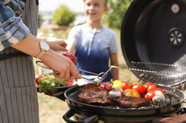 Happy family having barbecue with modern grill outdoors - Фото, зображення