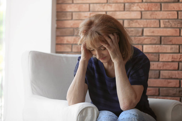 Senior vrouw lijdt aan depressie in leunstoel - Foto, afbeelding