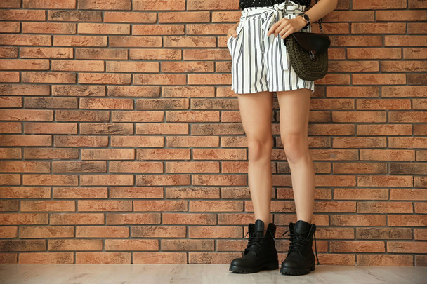 Young woman with sexy legs near brick wall - Φωτογραφία, εικόνα