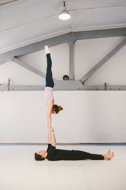 paspaslar üzerinde beyaz bir spor salonunda akrobatik yoga uygulamak Genç beyaz erkek ve kadın bir çift. Mill, konum türü L-Bass, zorluk gerçekten zor kişi 2 kişi sayısı becerileri Loy el, Rüzgar. - Fotoğraf, Görsel