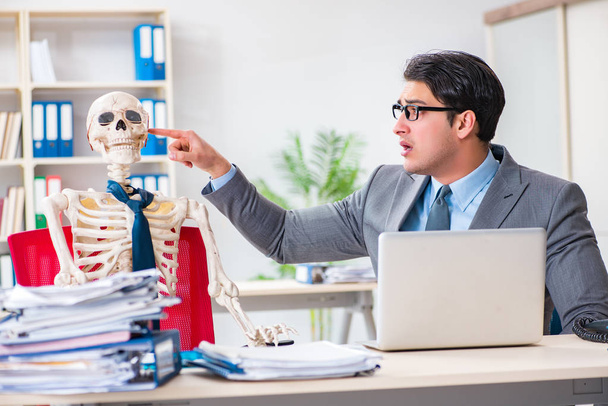 Businessman working with skeleton in office - Photo, Image