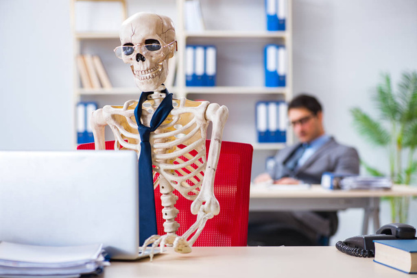 Бізнесмен, що працює зі скелетом в офісі
 - Фото, зображення
