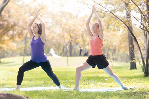 Mujer joven de vacaciones haciendo yoga posan meditación en el parque público Deporte Concepto saludable
. - Foto, imagen