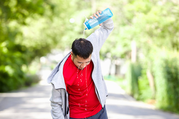 Asiatische Sportler trinken Wasser nach dem Laufen im Park - Foto, Bild