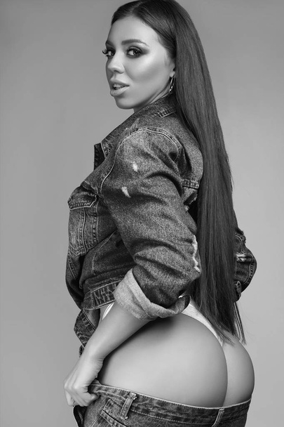 Portrait of gorgeous beautiful sexy brunette with perfect body wearing jeans jacket on gray background - Photo, Image