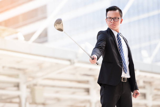 Retrato asiático hombre de negocios jugando al golf con paisaje urbano en el fondo
 - Foto, imagen