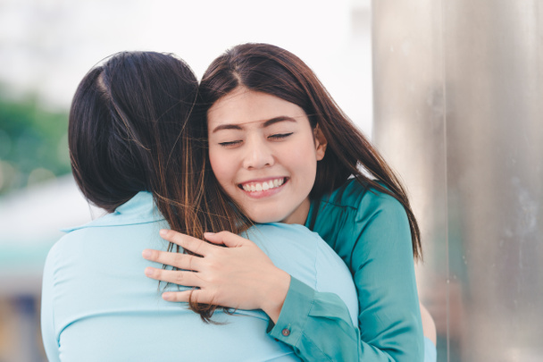 Portrait of happy asian women hugging each friend outdoor city background - Photo, Image