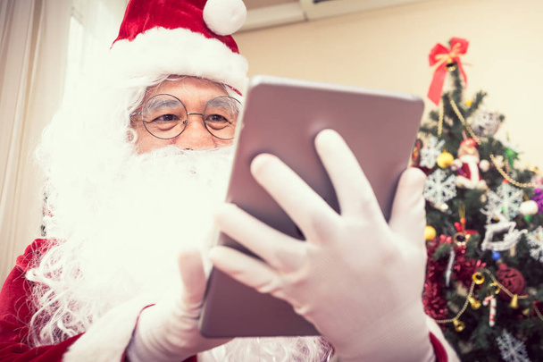 Papai Noel segurando jogar tablet, conceito de Natal
 - Foto, Imagem