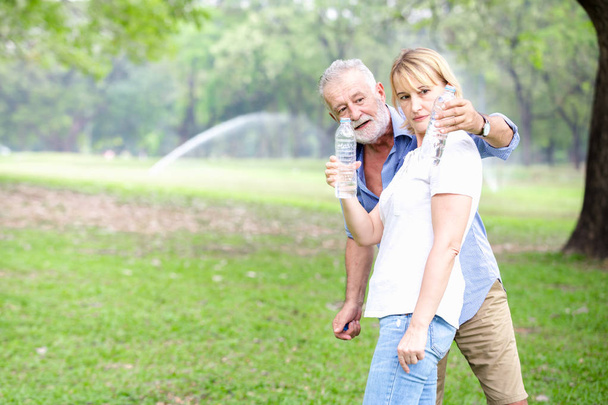 Πορτρέτο ανώτερος ζευγάρι στέκεται πόσιμο νερό στο πάρκο - Φωτογραφία, εικόνα