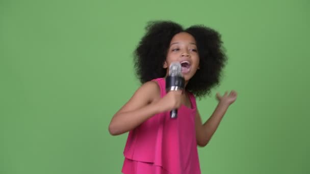 Young cute African girl with Afro hair singing happily - Séquence, vidéo