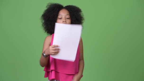 Young cute African girl with Afro hair ripping paperwork - Materiał filmowy, wideo