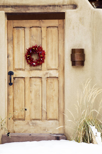 Венок Красный Чили Ristra висит на деревянной двери, Санта-Фе, Нью-Мексико
 - Фото, изображение