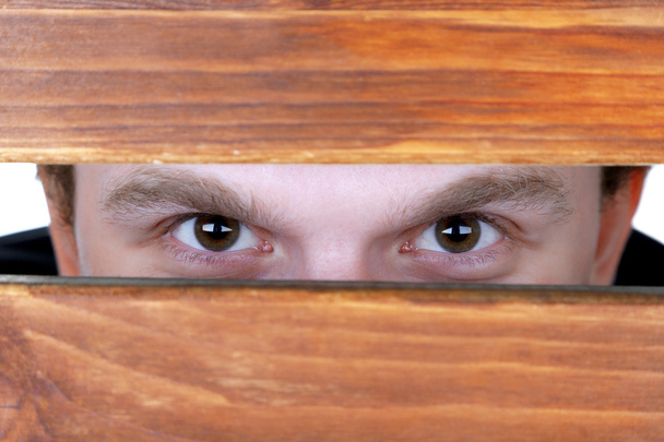 Man eyes looking through hole in wooden desk - Zdjęcie, obraz