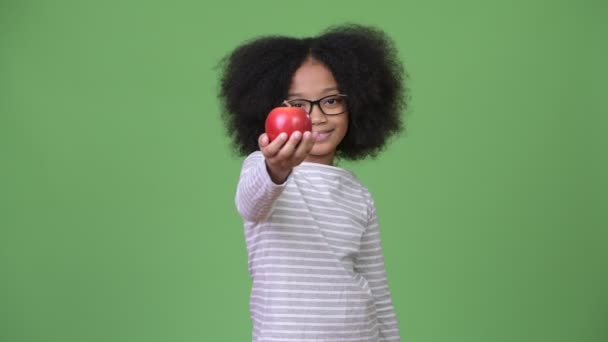 Young happy African girl with Afro hair holding apples - Imágenes, Vídeo