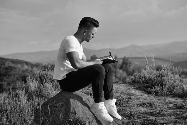 lonely man writes a letter to his beloved. Pensive muscular man with book outdoor - Photo, Image