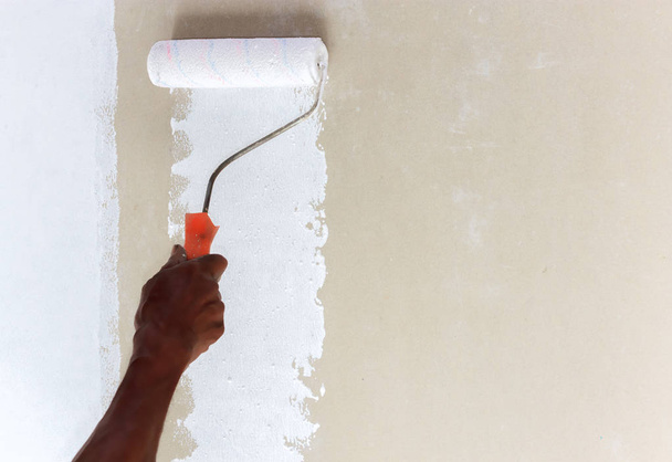 Someone layering a flat surface with white color paint using a paint roller. - Photo, Image