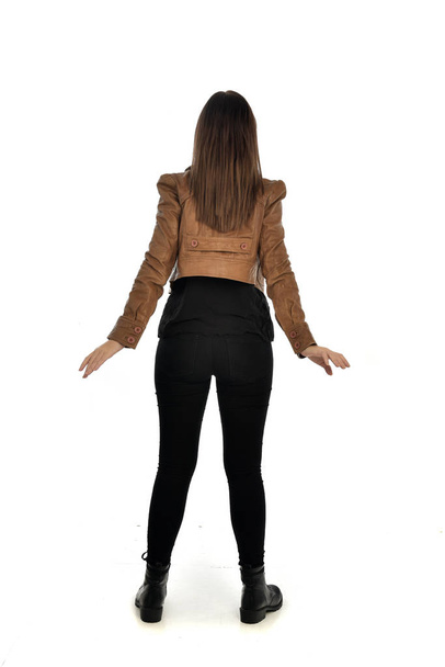 full length portrait of brunette girl wearing leather jacket and plain black clothes. standing pose, isolated on white studio background. - Fotografie, Obrázek