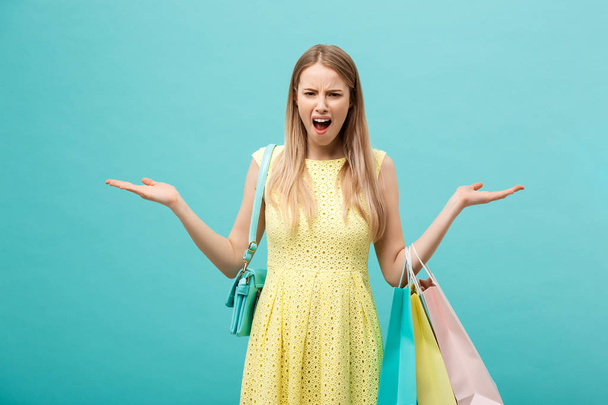 Zakupy i sprzedaż Concept: piękna nieszczęśliwa młoda kobieta w żółtej eleganckiej sukience z torbą na zakupy. - Zdjęcie, obraz