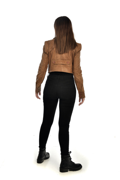 full length portrait of brunette girl wearing leather jacket and plain black clothes. standing pose, isolated on white studio background. - Fotoğraf, Görsel