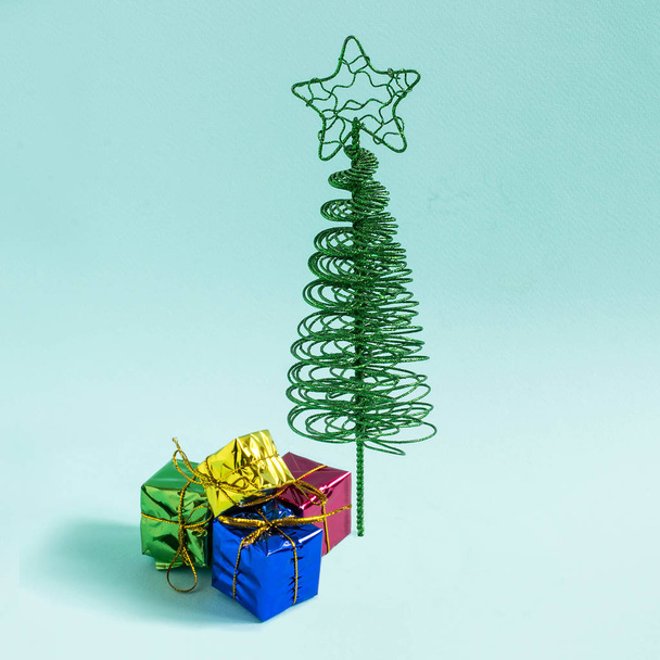 Small elegant Christmas tree made of wire and gifts on gradient blue background. Minimal style. Christmas and New Year concept - Fotoğraf, Görsel
