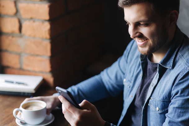 Bearded man using phone inside a restaurant while drinking coffee - Φωτογραφία, εικόνα