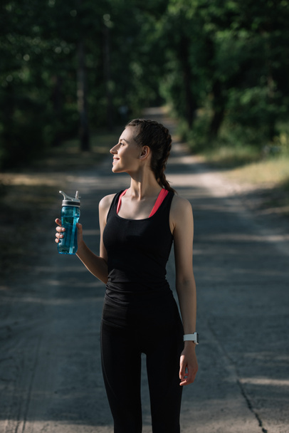 spor şişe su ile parkta tutan atletik kadın - Fotoğraf, Görsel
