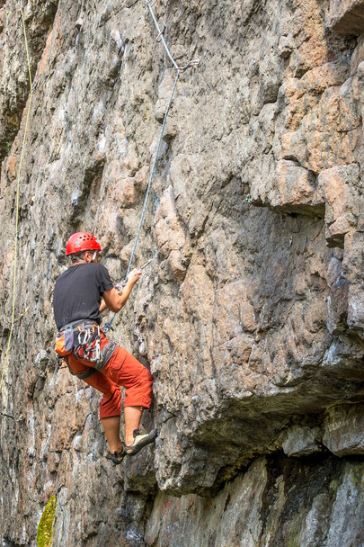 Скелелазіння. Молодий альпініст піднімається на вертикальний гранітний камінь. Екстремальні види спорту
 - Фото, зображення