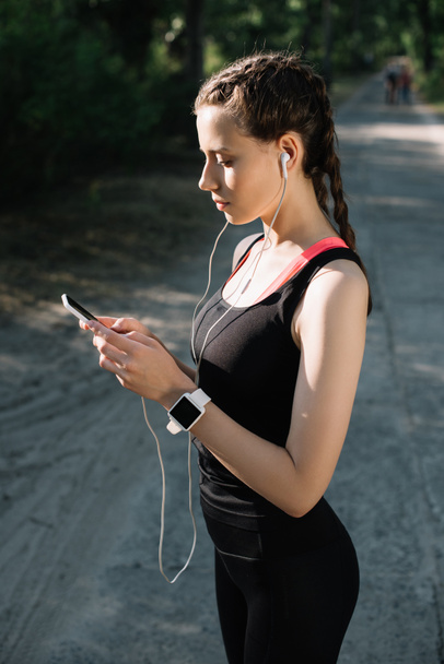 attractive sportswoman with earphones, smart watch and smartphone - Fotoğraf, Görsel