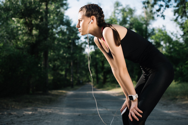 tired sportswoman listening music with earphones and smartphone - 写真・画像