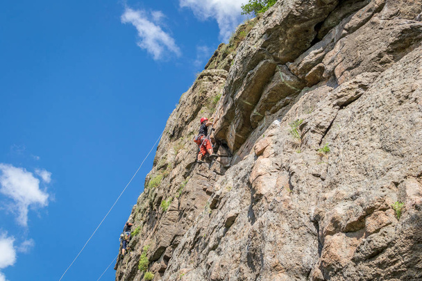 Скалолазание. Молодой альпинист взбирается на вертикальную гранитную скалу. Экстремальный спорт
 - Фото, изображение