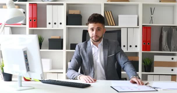 Geschäftsmann im Anzug sitzt in weißem Büro am Tisch und schüttelt negativ den Kopf - Filmmaterial, Video