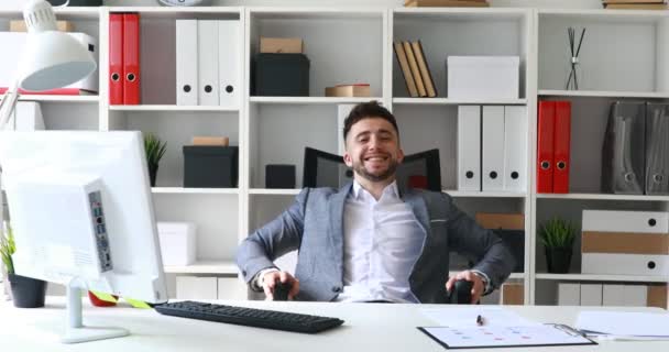 businessman in suit coat sitting at table in white office and rejoicing at success - Video