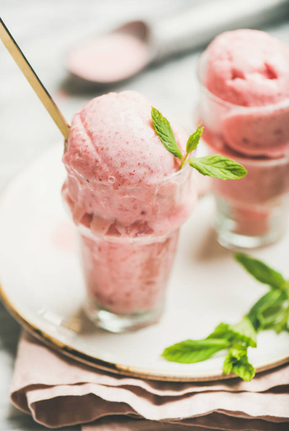 Homemade strawberry yogurt ice cream with fresh mint in glasses on plate over grey marble background - Fotoğraf, Görsel