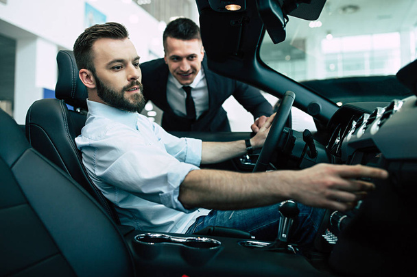 Bearded man buying new cabriolet at dealership, salesman showing him details - Fotografie, Obrázek