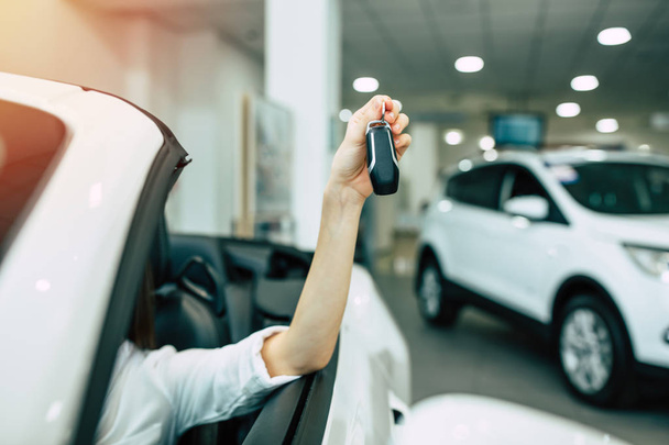 female hand holding car keys, woman sitting in car - Φωτογραφία, εικόνα