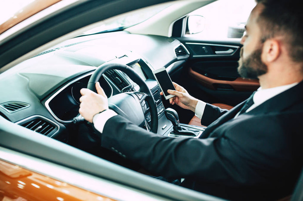 Confident man driving car using smartphone - Foto, Imagem