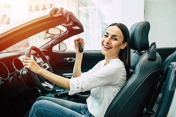 portrait of smiling beautiful woman driving new modern car and showing key - Foto, afbeelding
