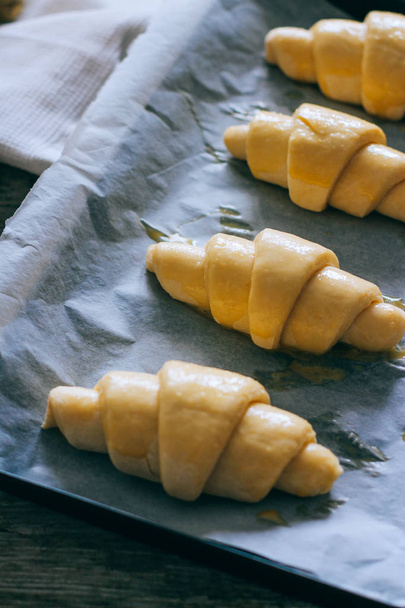 Croissants from homemade puff pastry on baking tray, greased with egg - 写真・画像