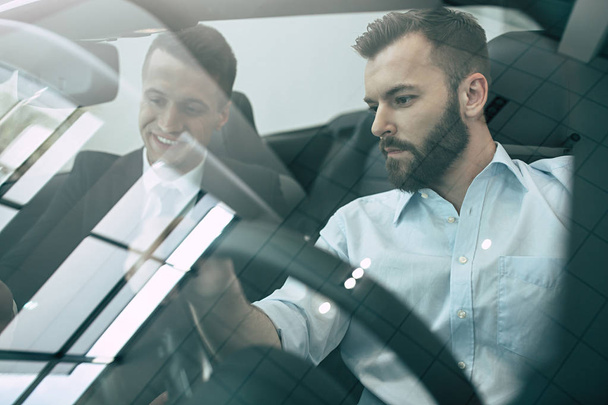two businessmen sitting in new cabriolet at dealership - Фото, зображення
